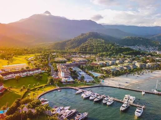 Marina com iates atracados, palmeiras e morros verdes ao fundo em Angra dos Reis